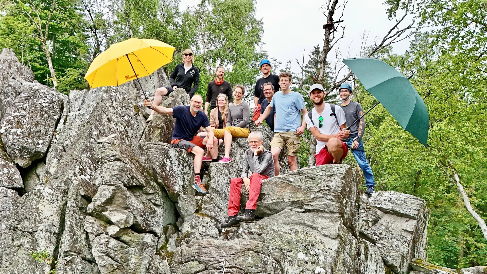Eine Gruppe von Kletterern am Fels, zwei halten Regenschirme in die Höhe | © Berenike Bernholt