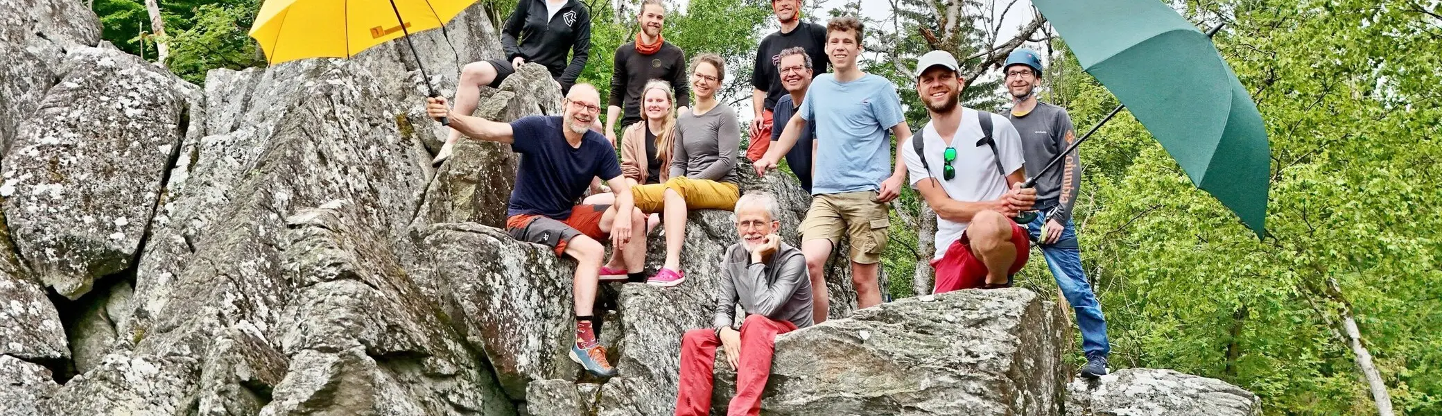 Eine Gruppe von Kletterern am Fels, zwei halten Regenschirme in die Höhe | © Berenike Bernholt