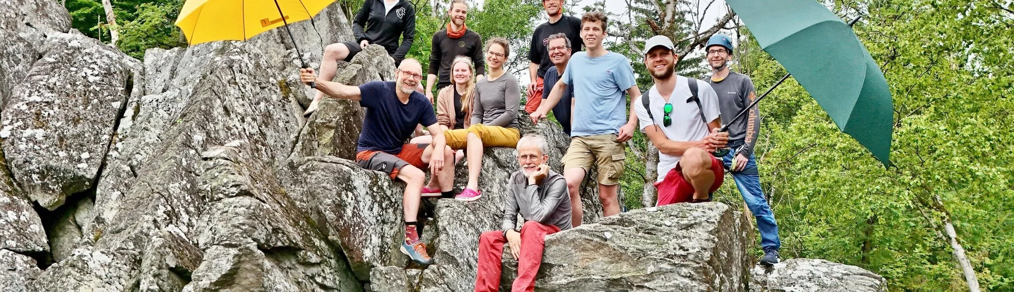 Eine Gruppe von Kletterern am Fels, zwei halten Regenschirme in die Höhe | © Berenike Bernholt