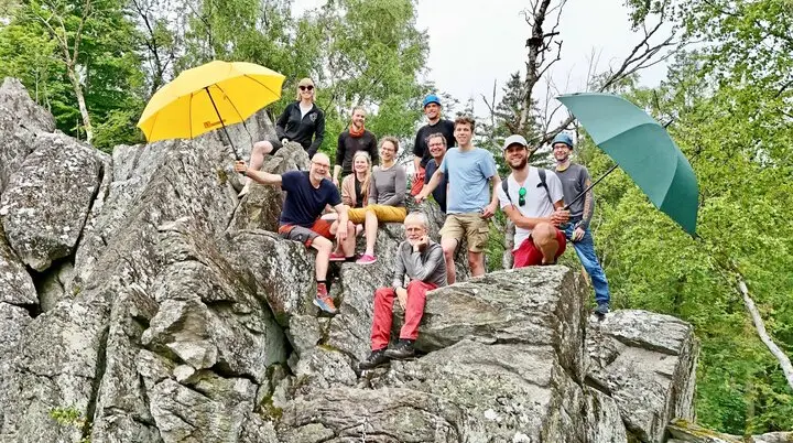Eine Gruppe von Kletterern am Fels, zwei halten Regenschirme in die Höhe | © Berenike Bernholt