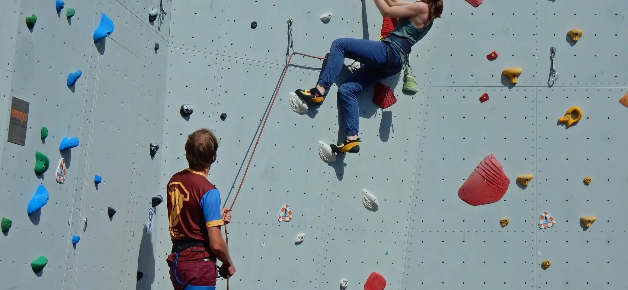 Eine Frau klettert an der Wand ein Mann sichert sie | © Kletterzentrum