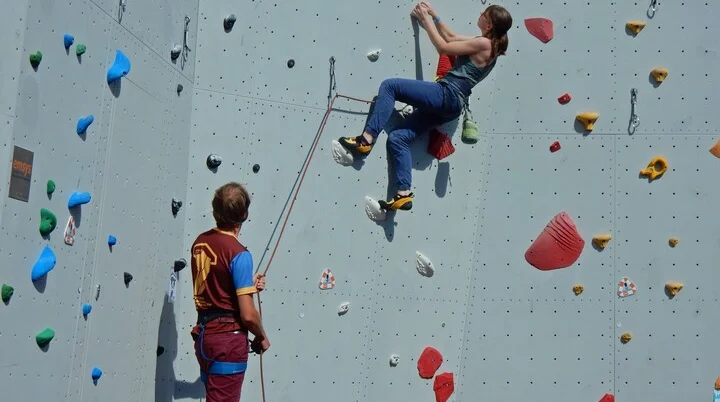 Eine Frau klettert an der Wand ein Mann sichert sie | © Kletterzentrum