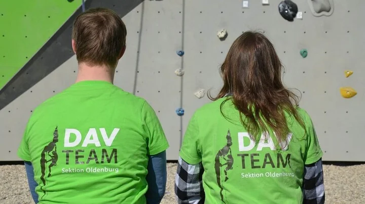 Zwei Kletterer sitzen mit dem Rücken zur Kamera, auf den Shirts steht DAV Team  | © Ralf Holtgrefe