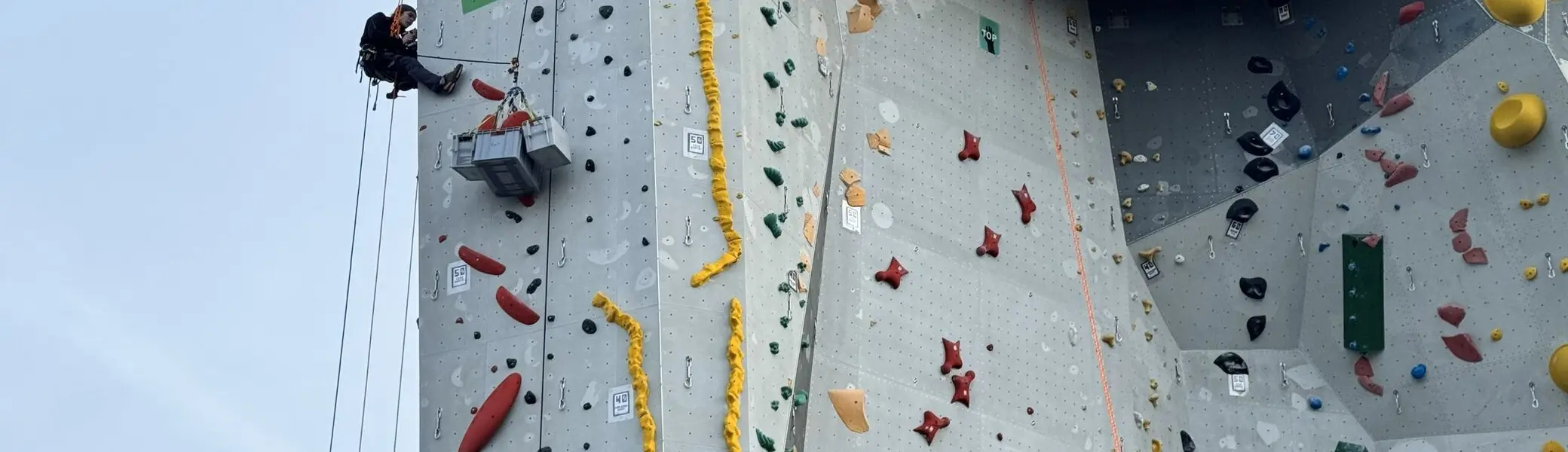 Zwei Kletterer schrauben die Griffe vom Kletterturm ab | © Kletterzentrum