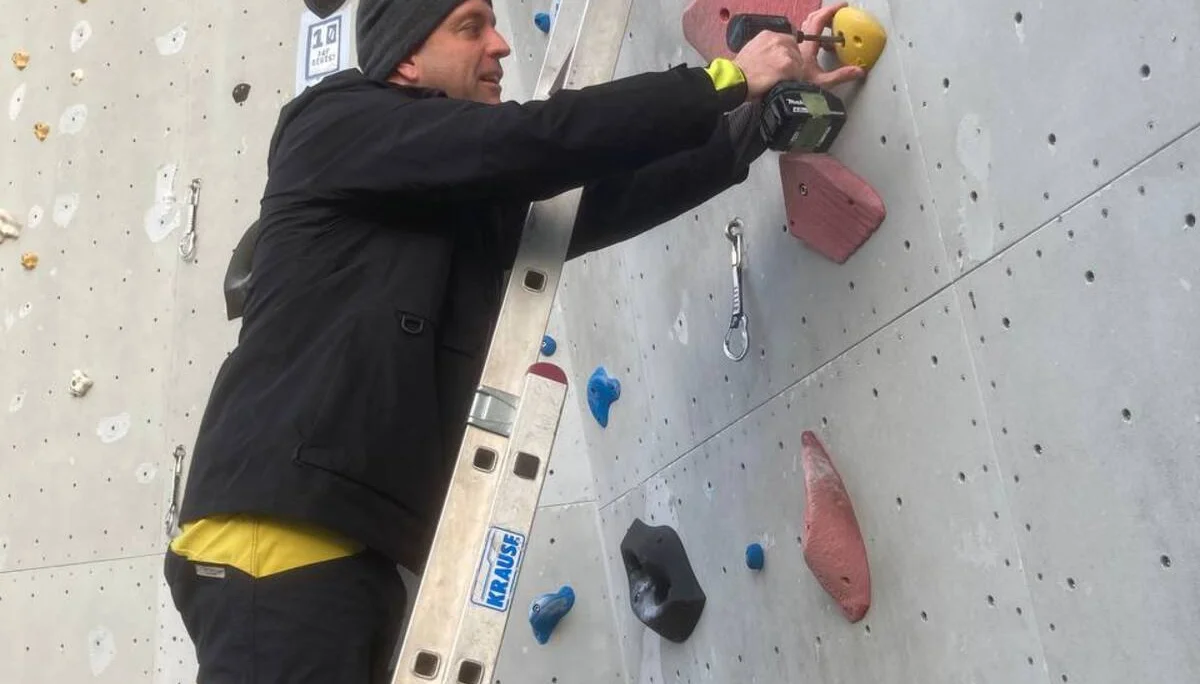 Ein Mann schraubt Klettergriffe an | © Kletterzentrum