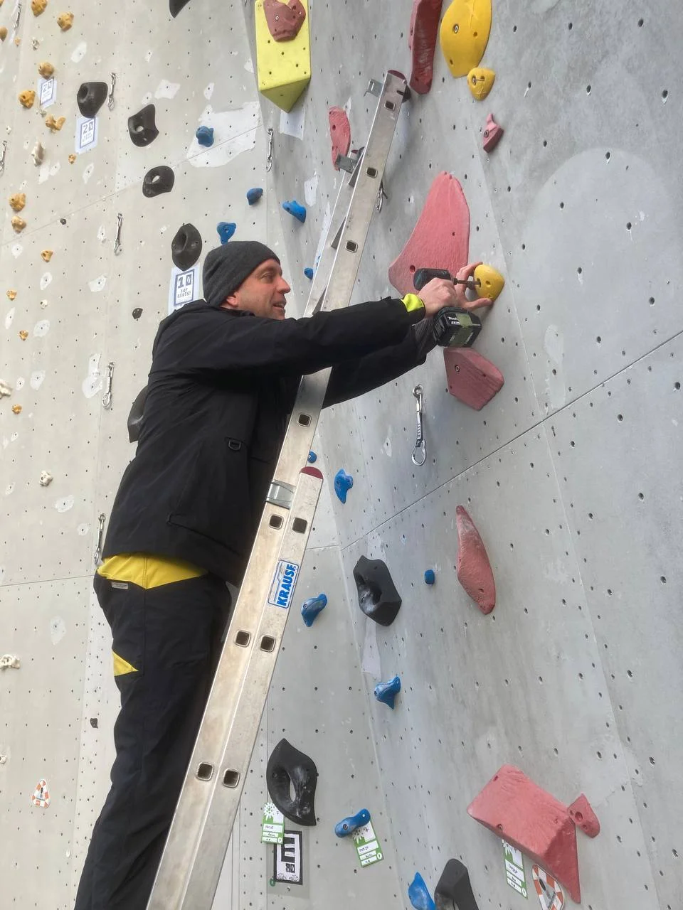 Ein Mann schraubt Klettergriffe an | © Kletterzentrum