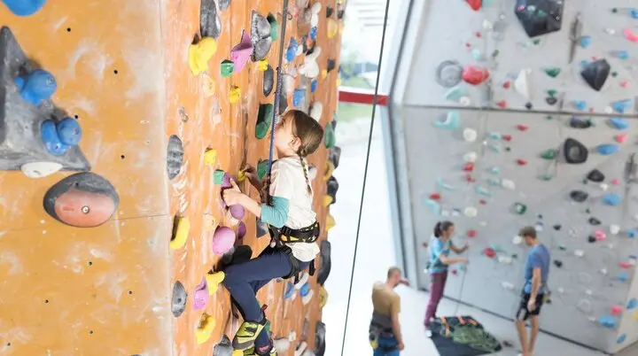 Ein Mädchen beim Familienklettern in der Kletterhalle des DAV. Im Hintergrund weitere Kletterer | © DAV / Jens Klatt